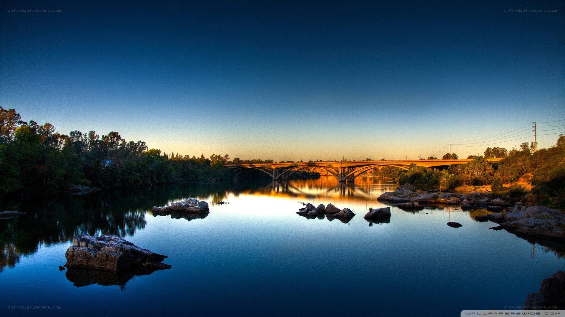 Bridge over calm river at sunset