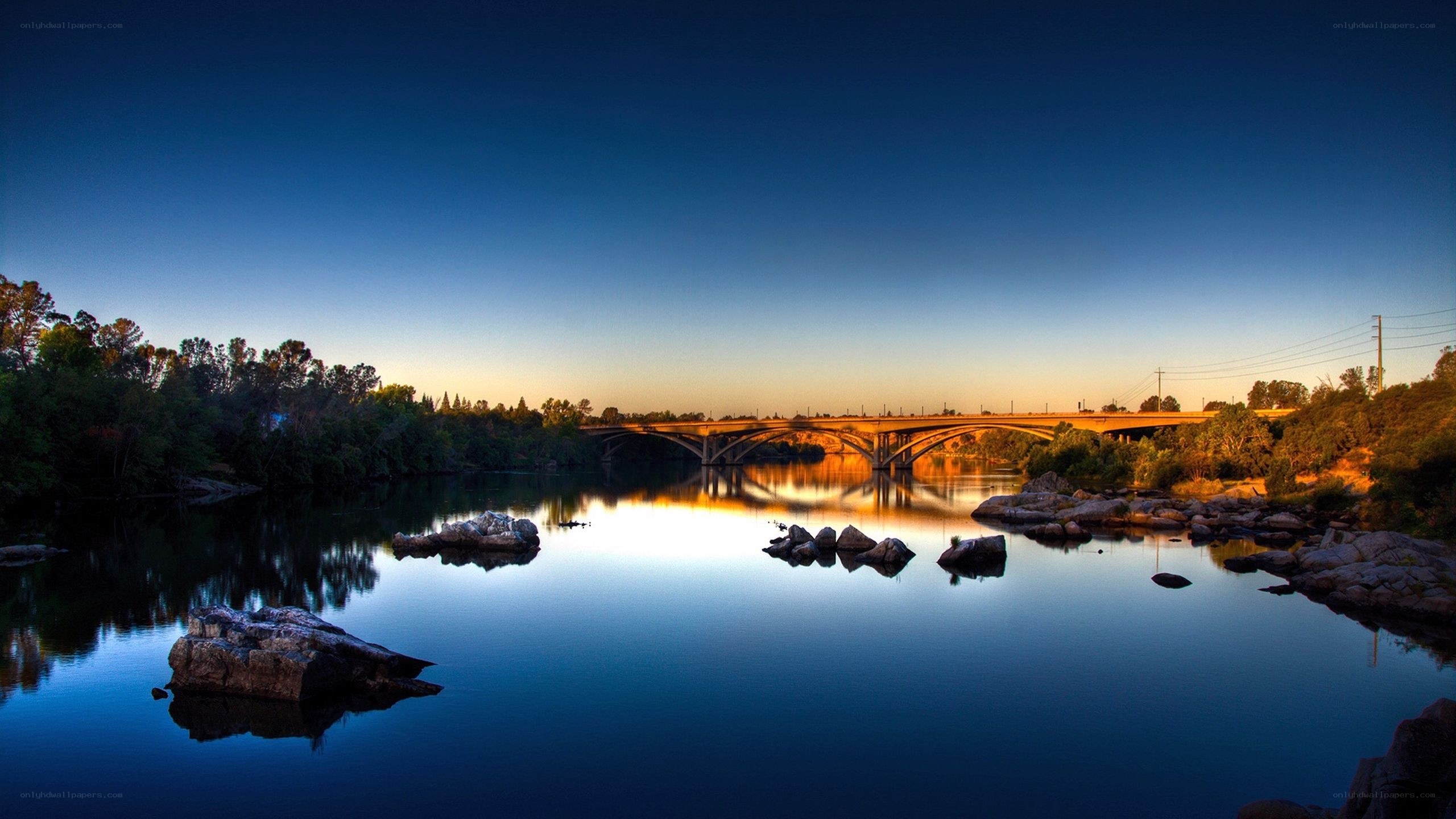 Bridge over calm river at sunset