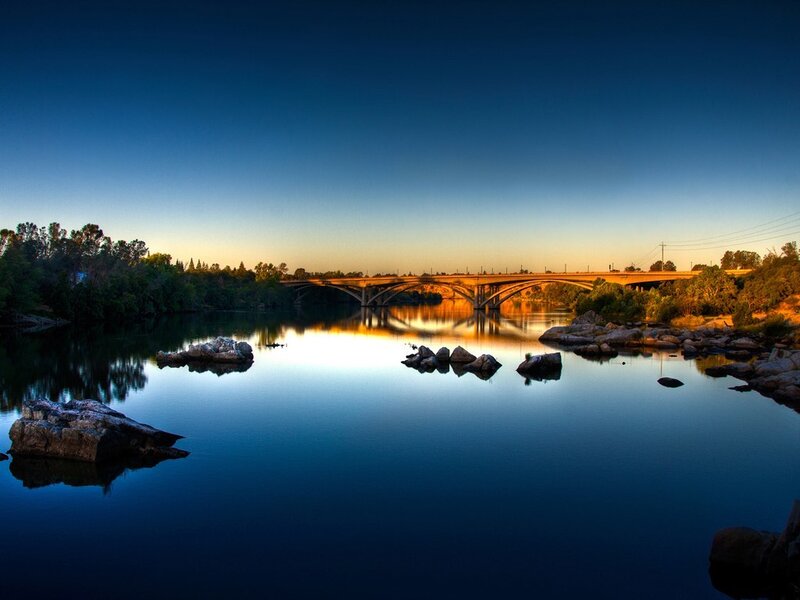 Bridge over calm river at sunset