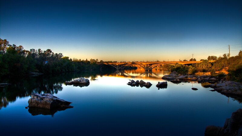 Bridge over Calm River — Blue, Serene, Sunset, Photograph, Rocks