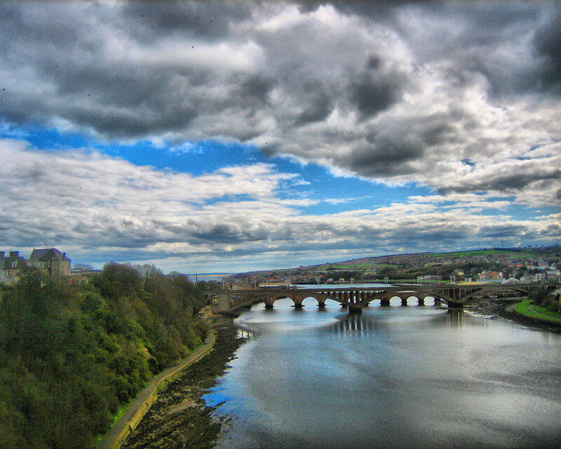 Bridge over river under cloudy sky
