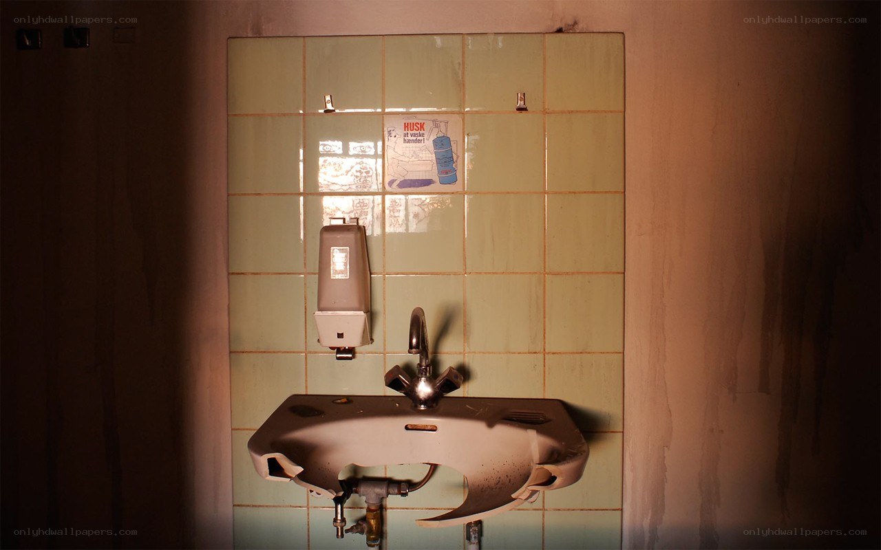 Broken sink in a tiled room