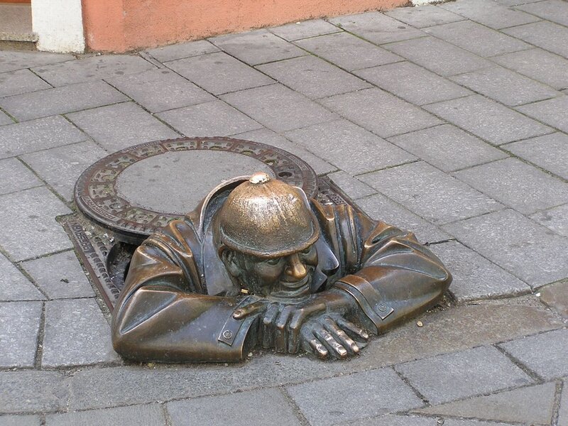 Bronze statue of man emerging from sewer