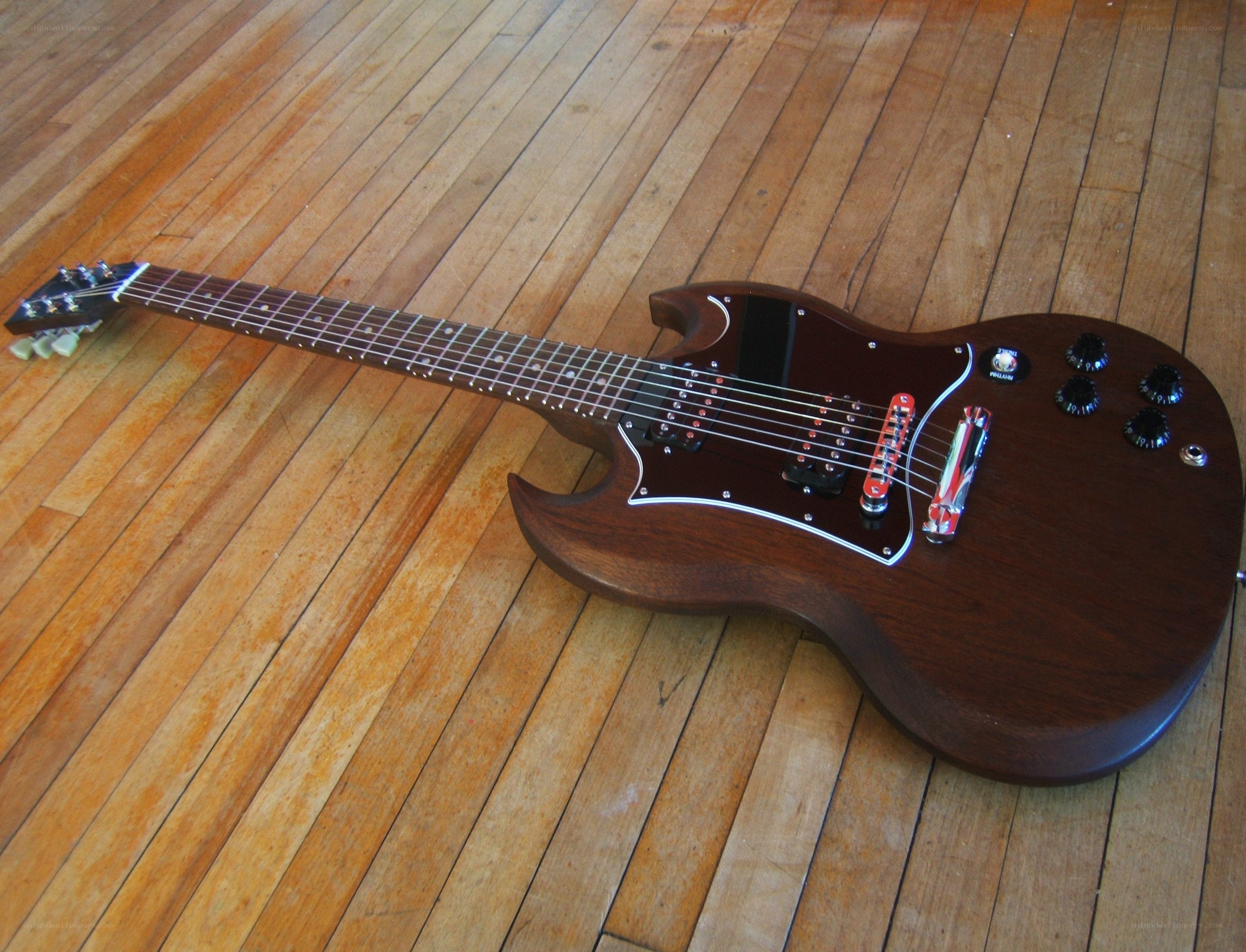 brown electric guitar on floor
