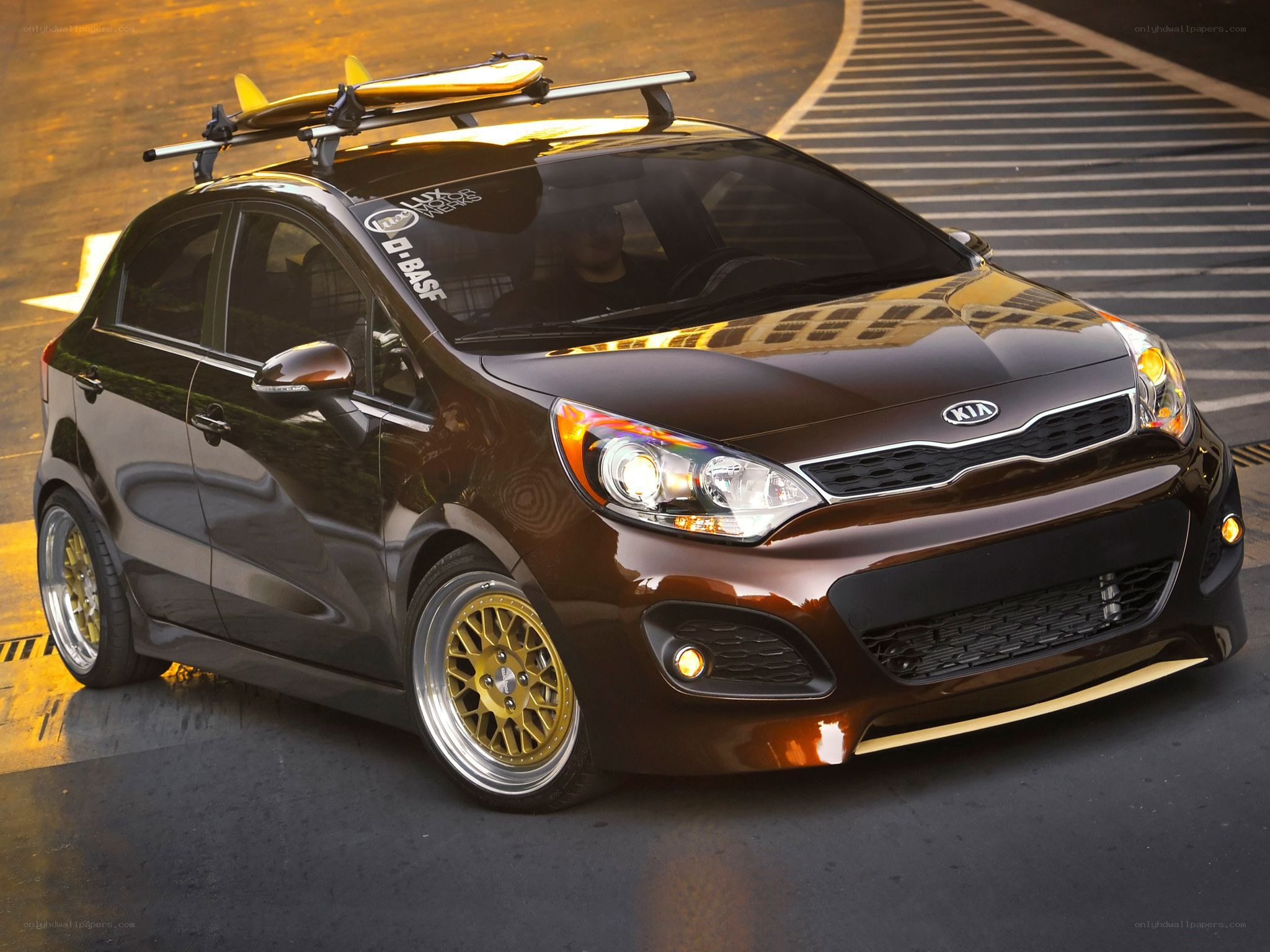 Brown Kia Rio with surfboard