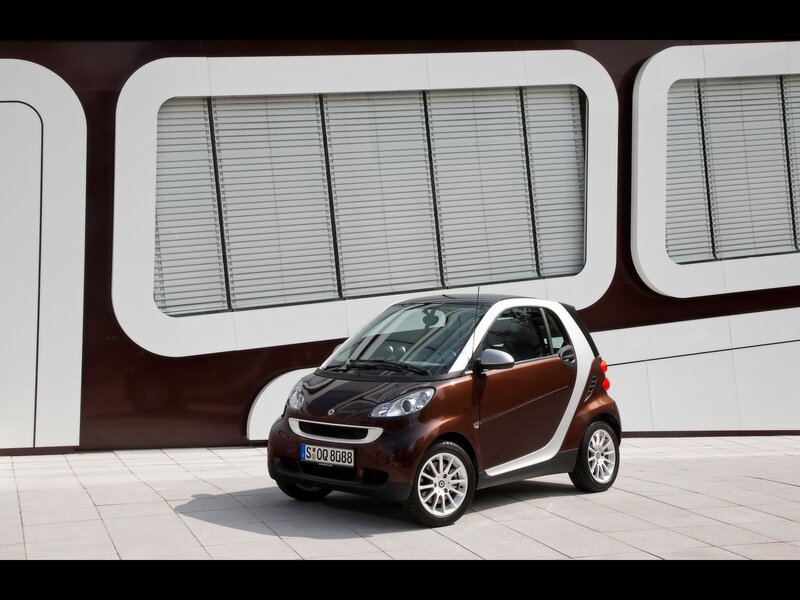 Brown smart car in front of modern building