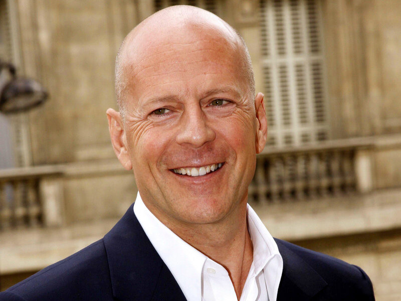 Bruce Willis smiling in a suit