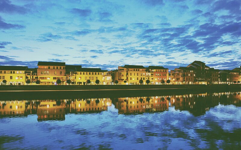 Buildings Along Riverbank — Blue, Serene, Night, Photograph, River, Sky, Trees