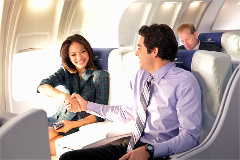 Business travelers shaking hands on plane