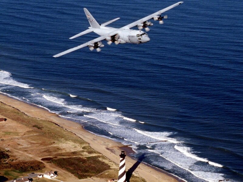 C-130 Hercules over coastal lighthouse