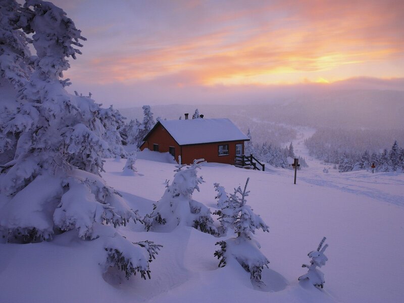 Cabin in snowy landscape at sunset