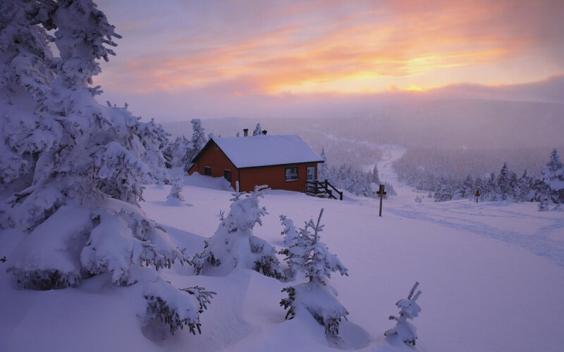 Cabin in snowy landscape at sunset