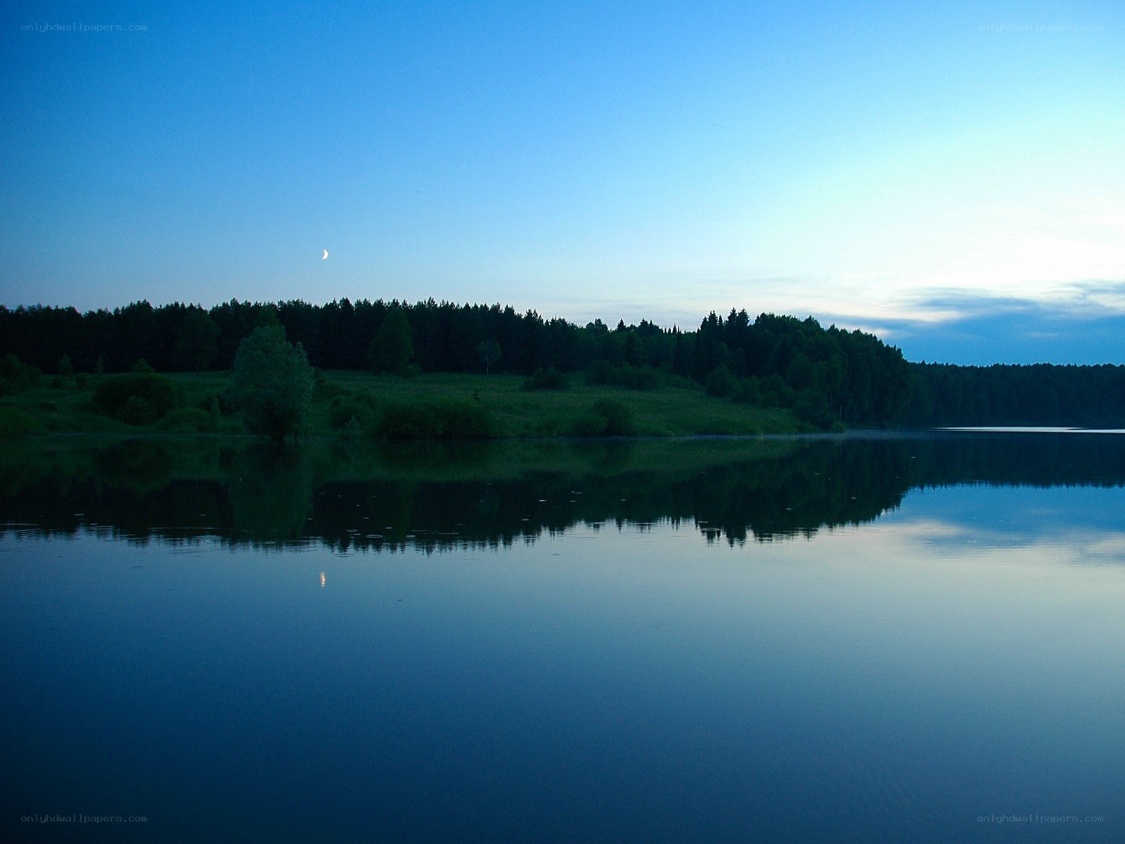Calm lake at dusk with moon