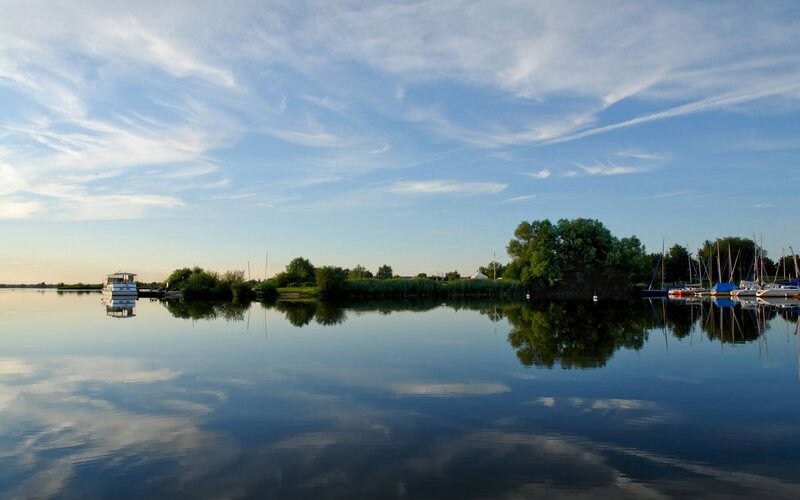 Calm lake with boats at sunset