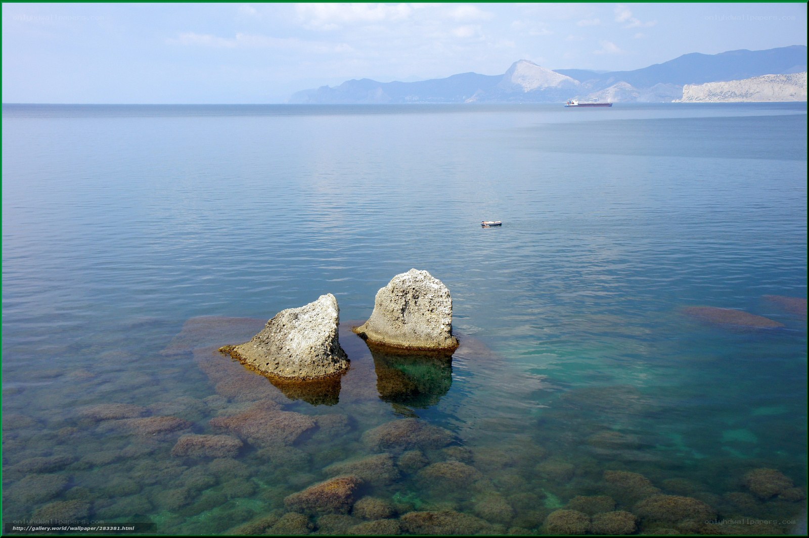 Calm sea with rocks and distant ship
