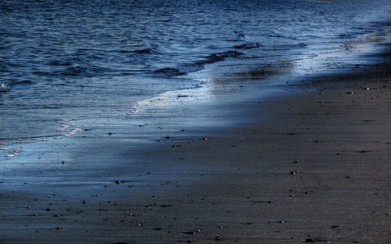 calm waves on dark sand