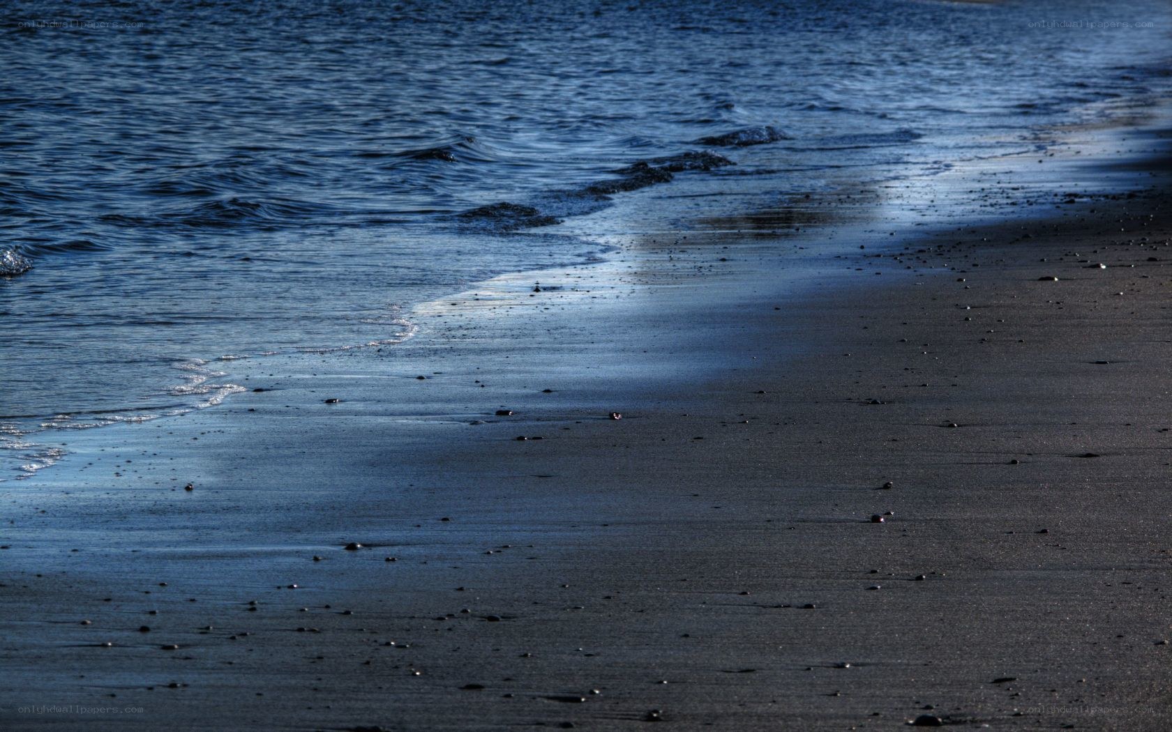 calm waves on dark sand