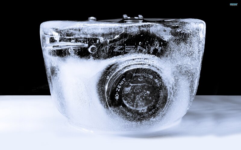 Camera in Ice Block — White, Dramatic, Photograph, Black Background, White Surface