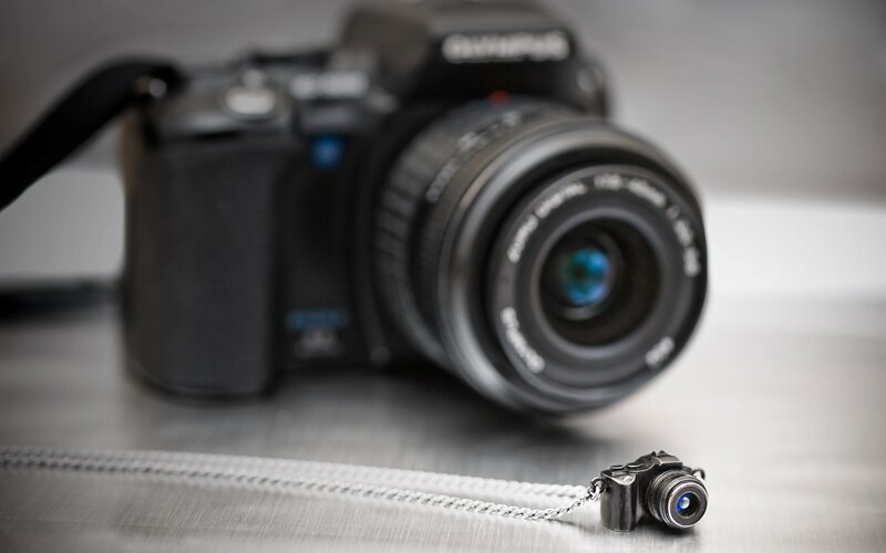Camera necklace with DSLR in background