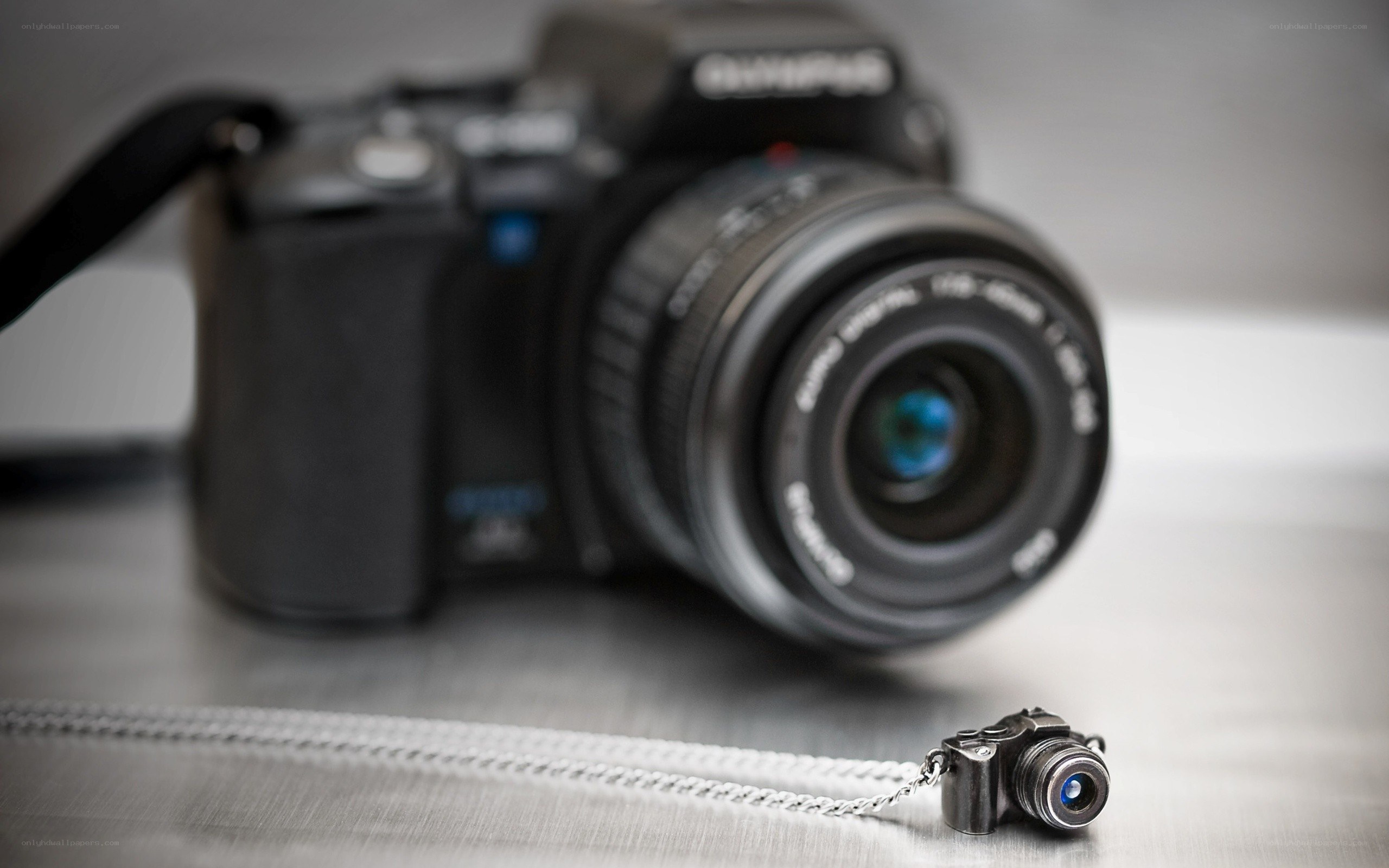 Camera necklace with DSLR in background