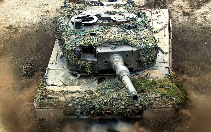 camouflaged tank in muddy terrain
