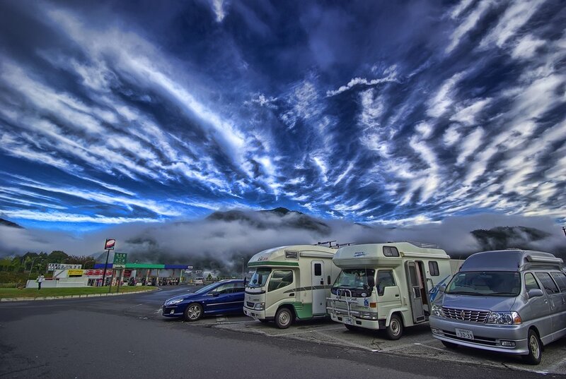 Campers at a gas station under dramatic sky