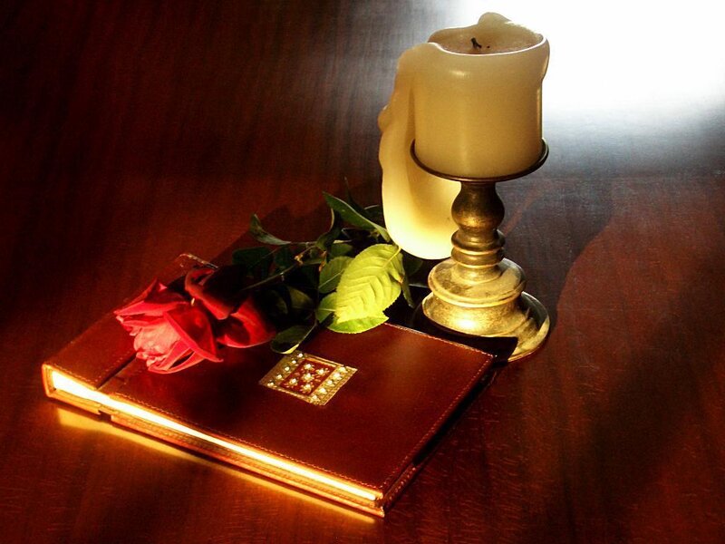 candle and rose on book