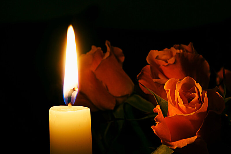 Candle and roses in darkness