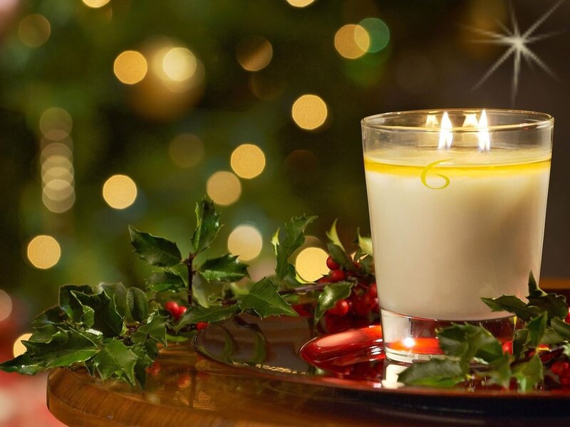 Candle with holly on table