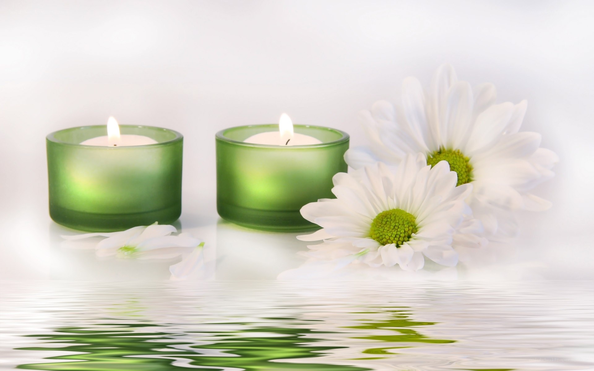 Candles and daisies by water