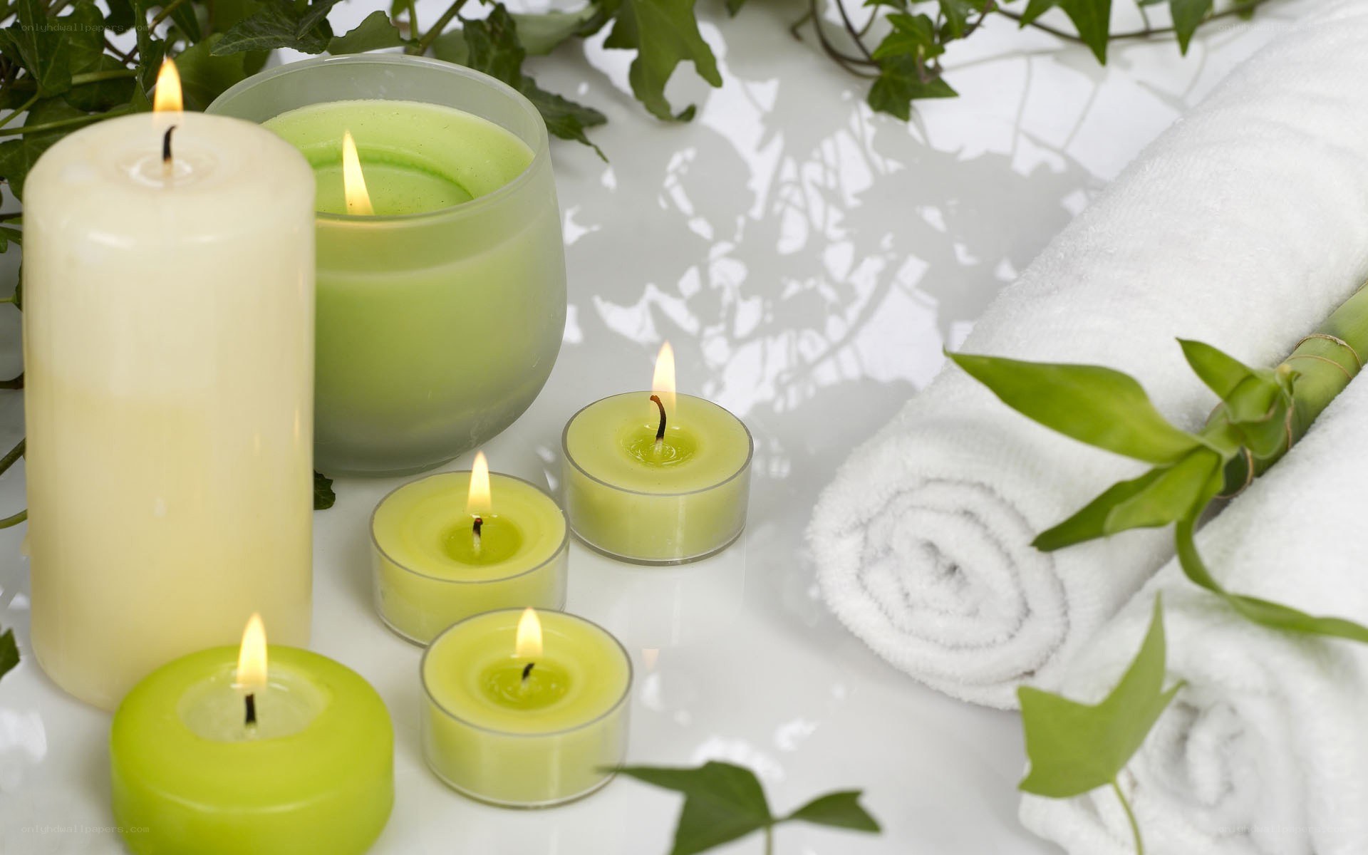 Candles and towels on white surface