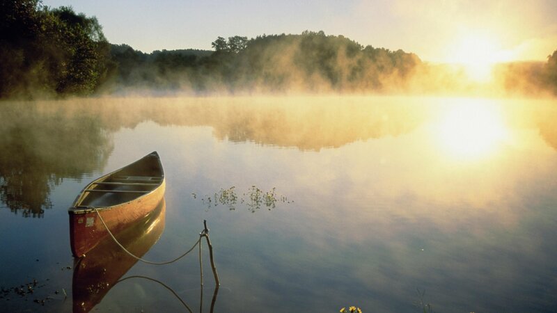 Canoe on misty lake at sunrise