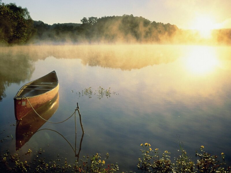 Canoe on misty lake at sunrise