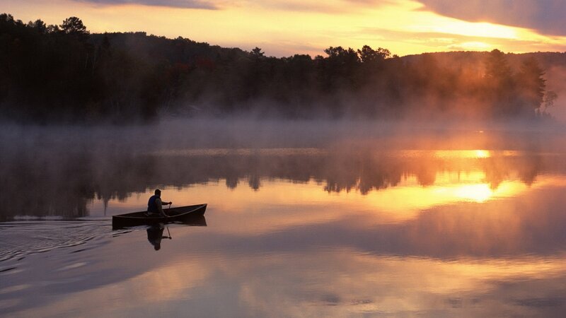 Canoeing at sunrise on a misty lake