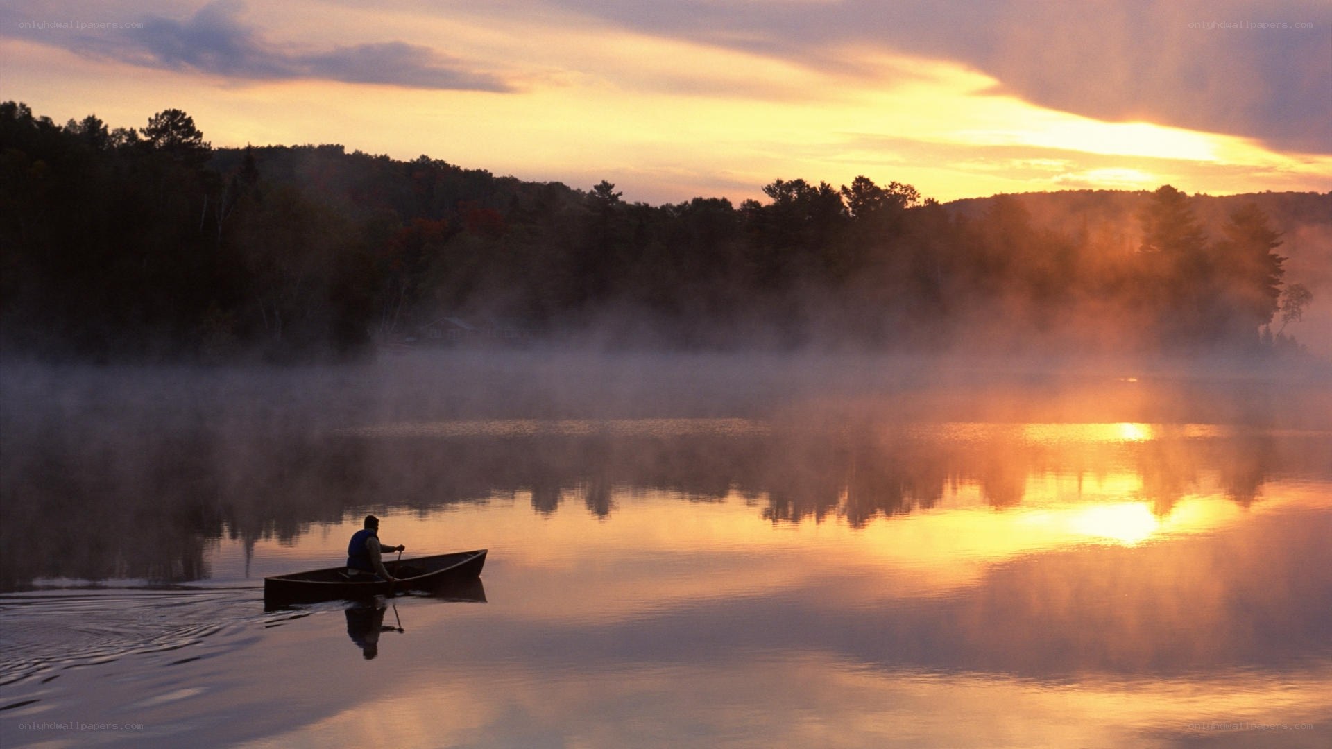 Canoeing at sunrise on a misty lake