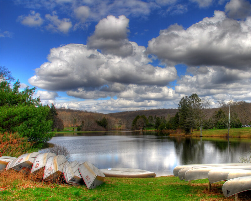 Canoes by a lake under cloudy sky