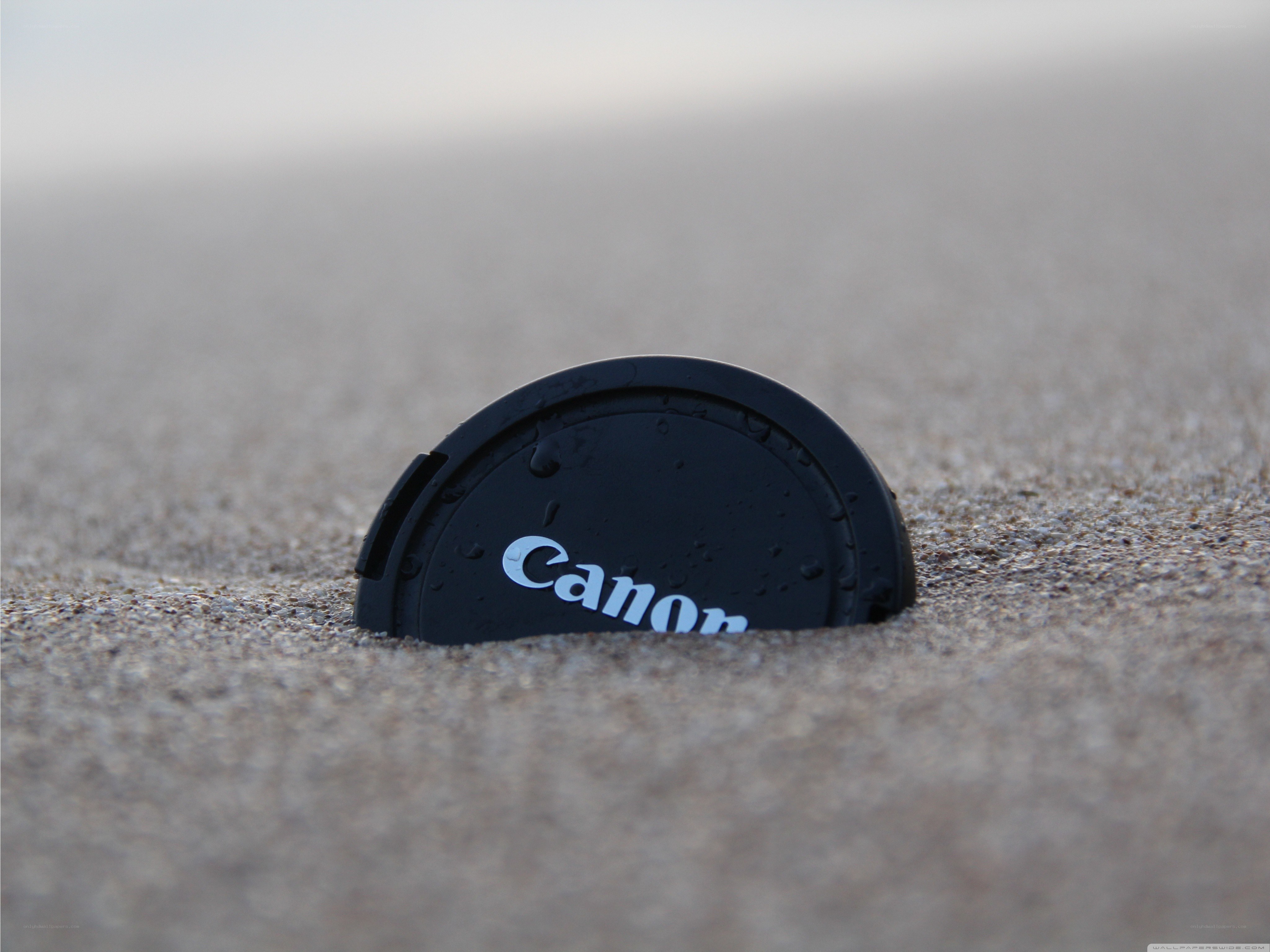 Canon lens cap on sandy beach