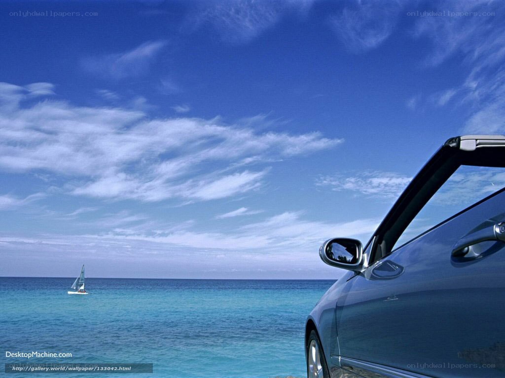 Car by the ocean with sailboat