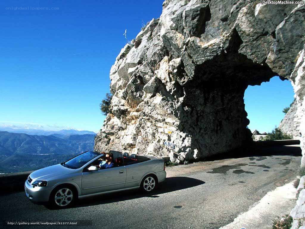 Car driving through rock arch