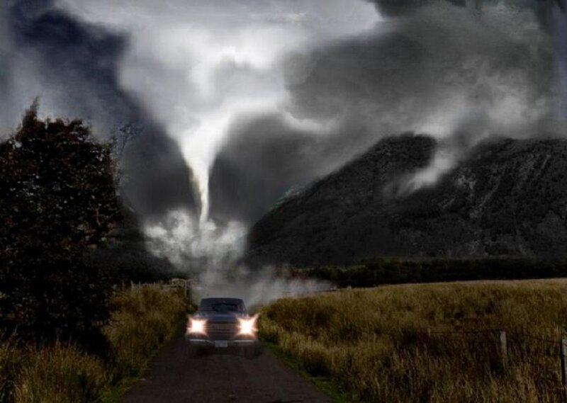 Car facing tornado in rural area