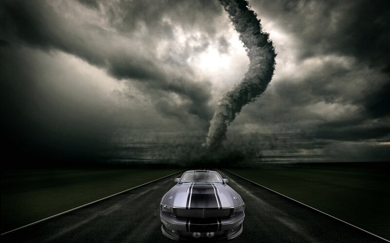 Car on road facing tornado