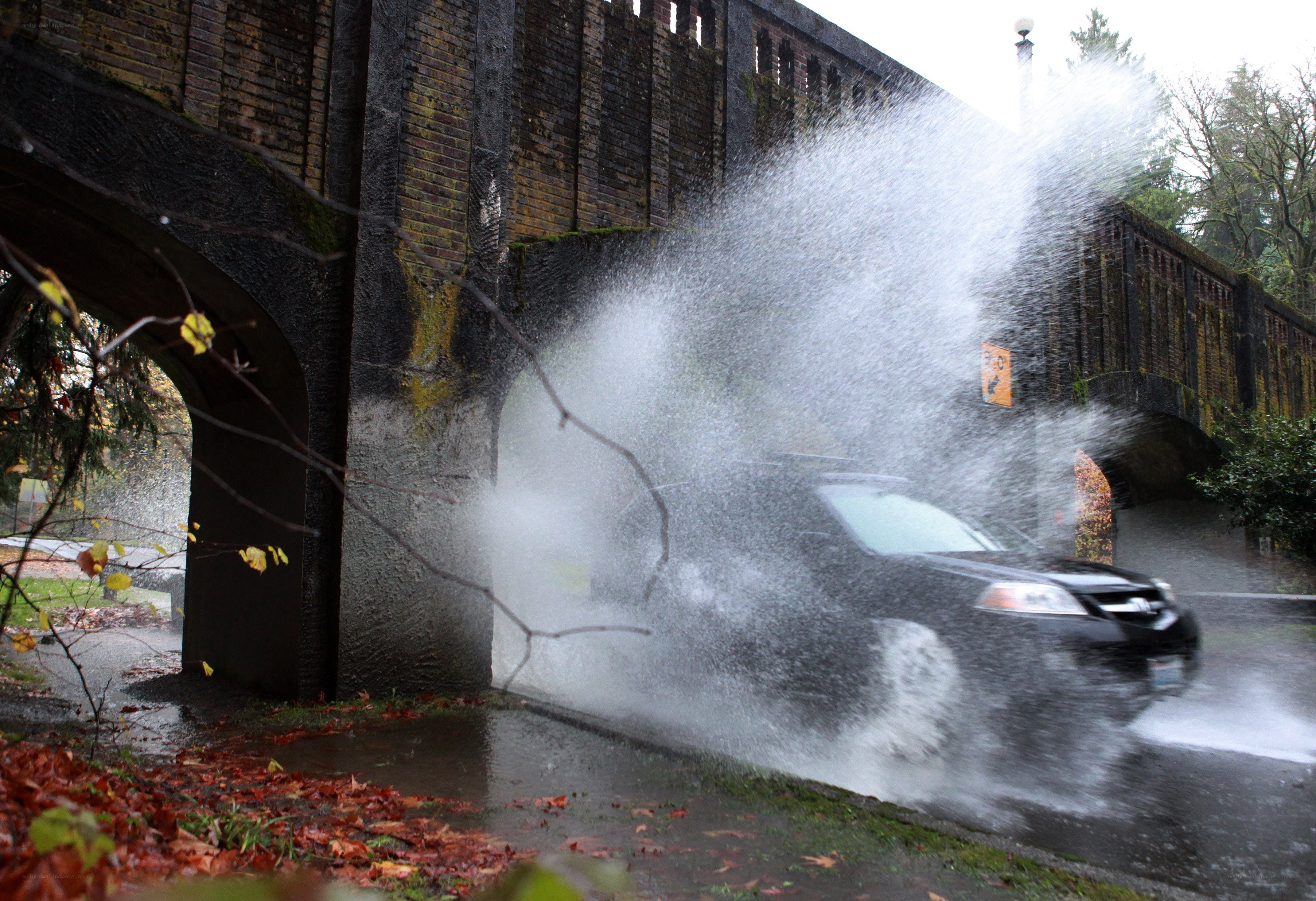 Car splashing water under bridge