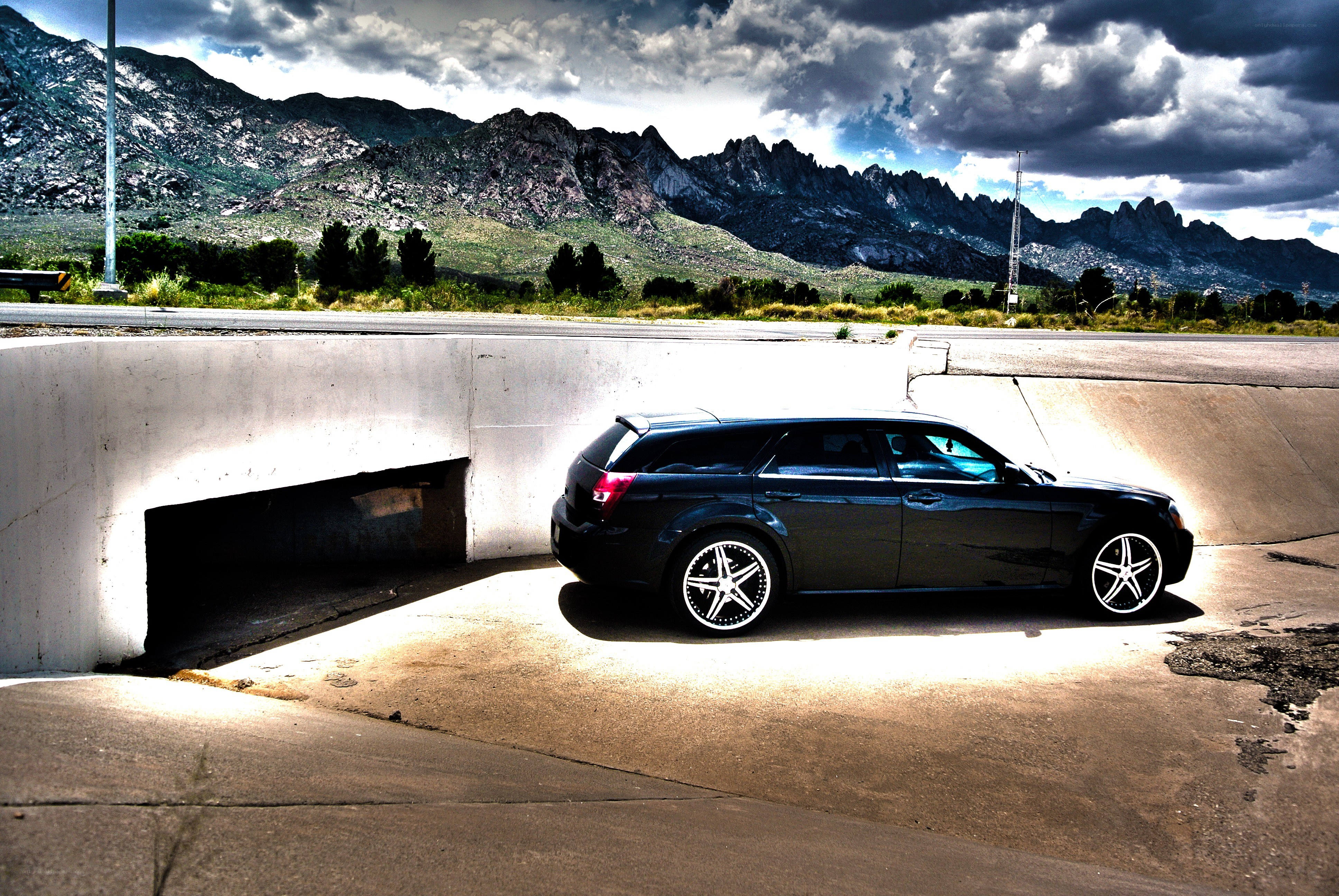Car under overpass with mountains