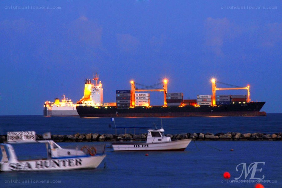 Cargo ship at dusk with boats
