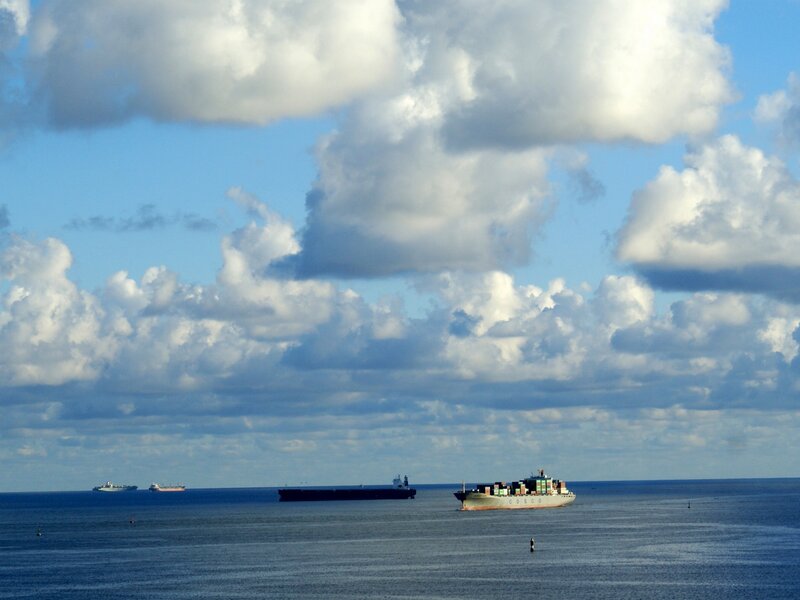 Cargo ships at sea under cloudy sky