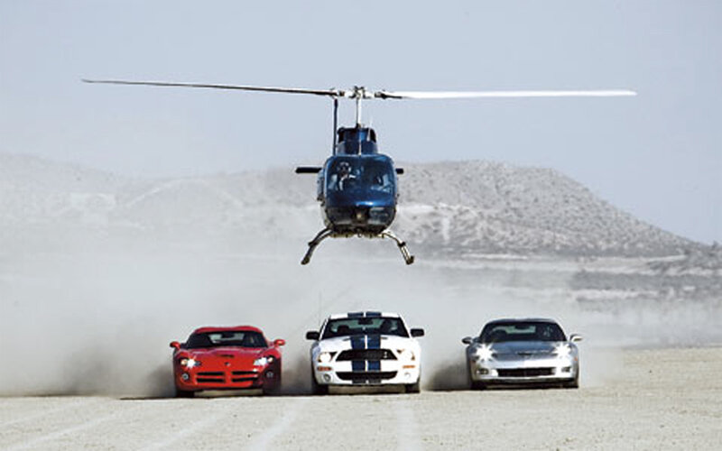 Cars racing with helicopter