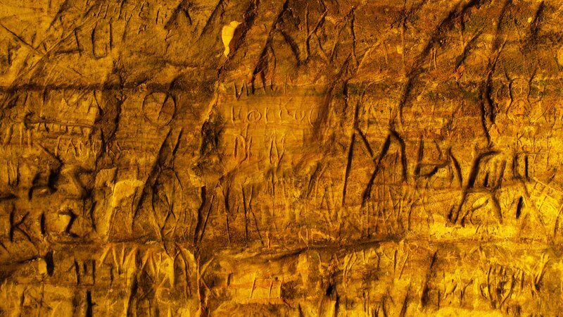 carved rock wall with graffiti