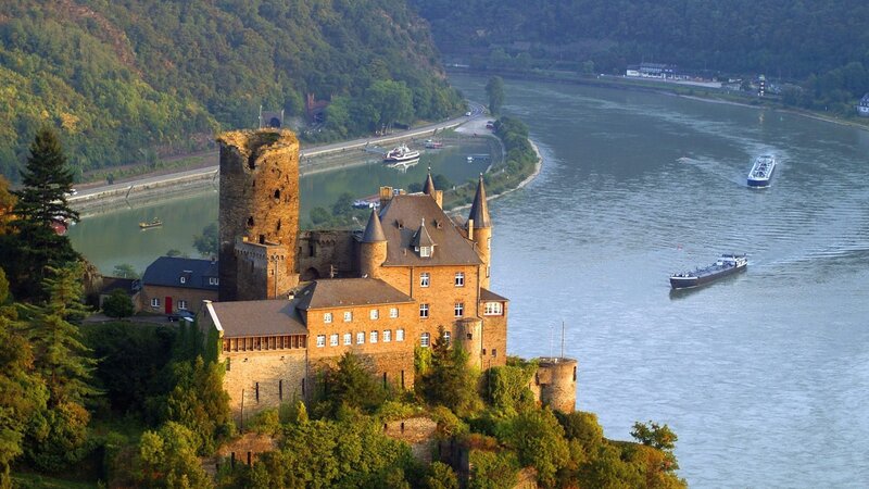 castle on riverbank with boats