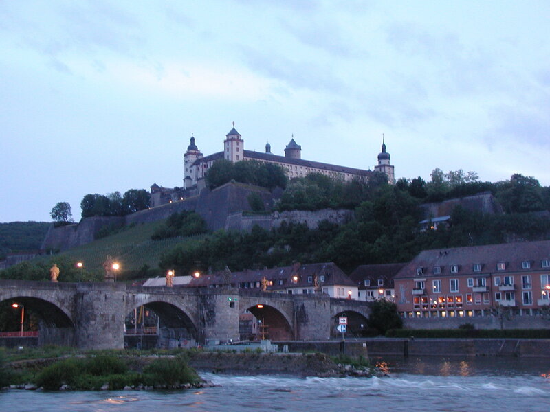 castle overlooking a river at dusk