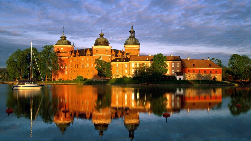 castle reflected in lake at sunset